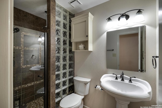 bathroom featuring sink, an enclosed shower, and toilet