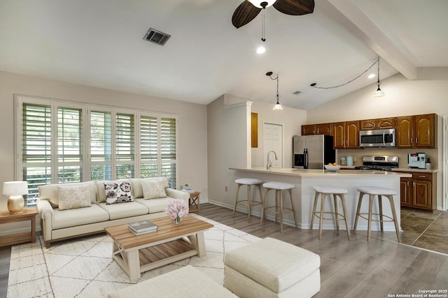 living room featuring vaulted ceiling with beams, ceiling fan, sink, and light hardwood / wood-style flooring