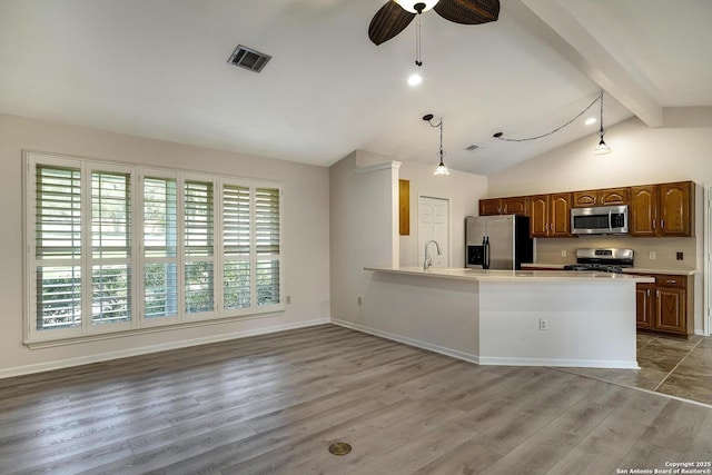 kitchen featuring lofted ceiling with beams, hanging light fixtures, ceiling fan, appliances with stainless steel finishes, and light hardwood / wood-style floors