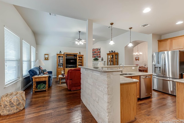 kitchen featuring pendant lighting, dark wood-type flooring, stainless steel appliances, an island with sink, and vaulted ceiling