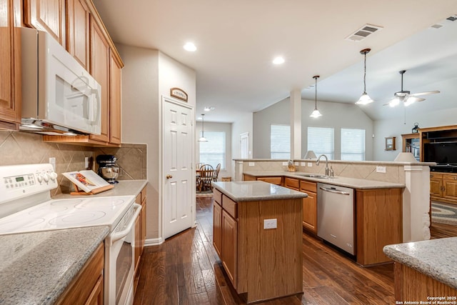 kitchen with lofted ceiling, sink, white appliances, backsplash, and a center island