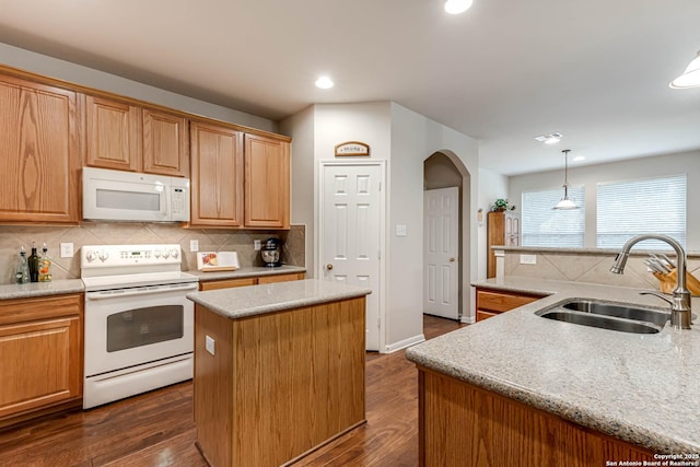 kitchen with decorative light fixtures, sink, dark hardwood / wood-style flooring, a kitchen island with sink, and white appliances