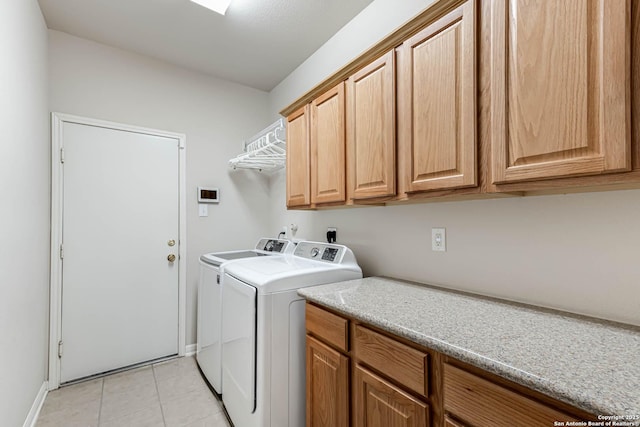 laundry room with cabinets, light tile patterned floors, and washer and dryer