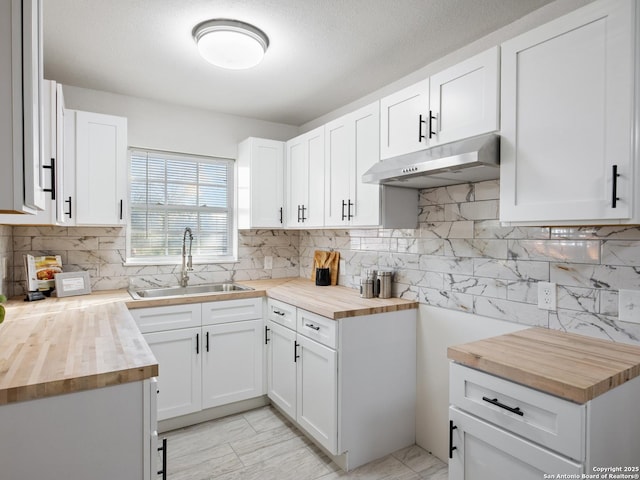 kitchen featuring wood counters, tasteful backsplash, white cabinetry, and sink