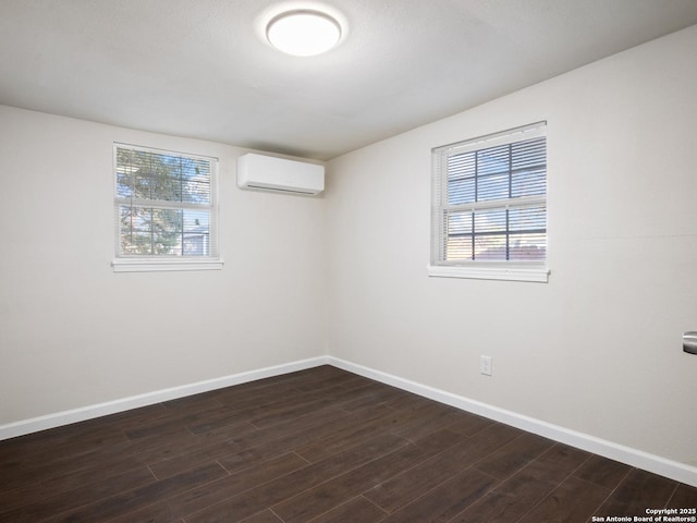 spare room featuring dark hardwood / wood-style flooring, a wealth of natural light, and a wall mounted AC