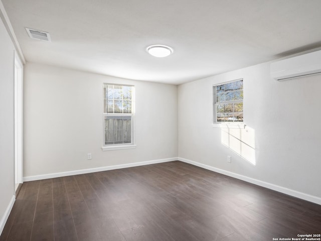 unfurnished room with dark hardwood / wood-style flooring and a wall mounted air conditioner