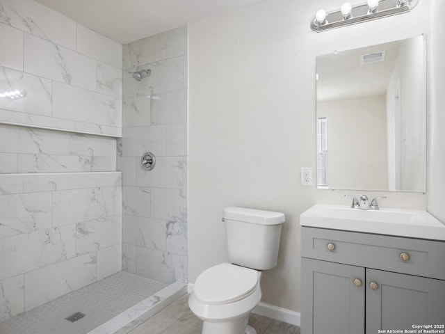 bathroom featuring tiled shower, vanity, and toilet