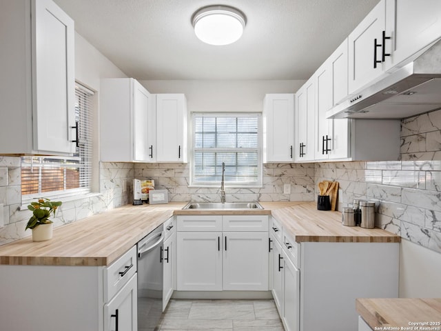 kitchen with dishwasher, wooden counters, white cabinets, sink, and range hood