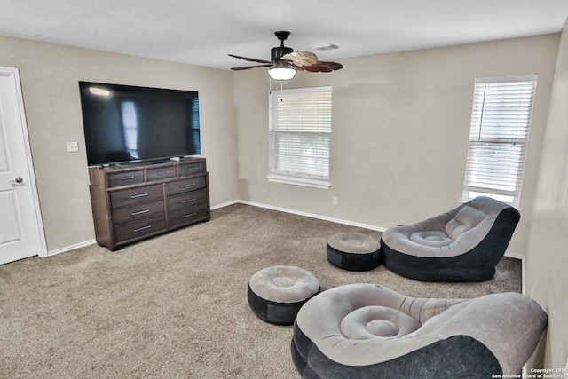 living area featuring carpet, ceiling fan, and a wealth of natural light