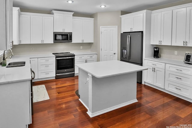 kitchen featuring stainless steel appliances, sink, a center island, dark hardwood / wood-style floors, and white cabinetry