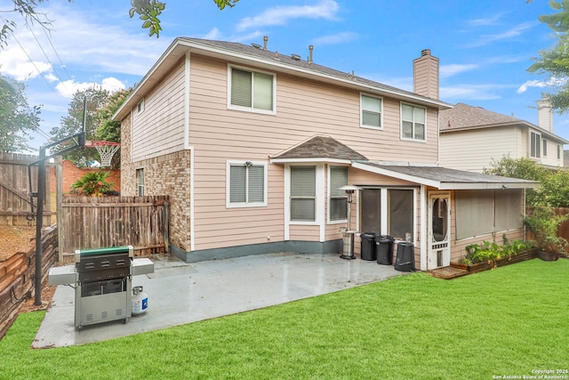 rear view of property featuring a lawn, a sunroom, and a patio