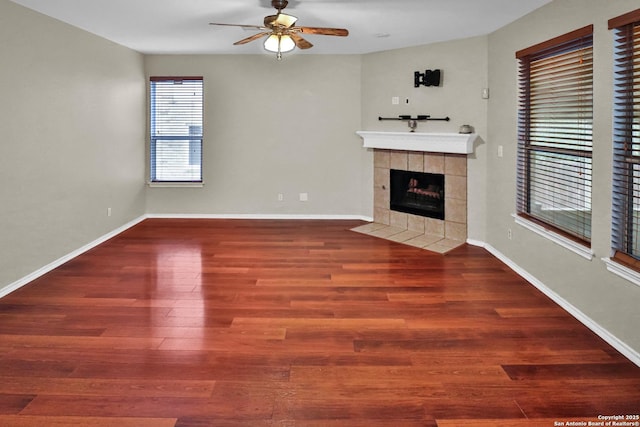 unfurnished living room with ceiling fan, dark hardwood / wood-style floors, and a tiled fireplace