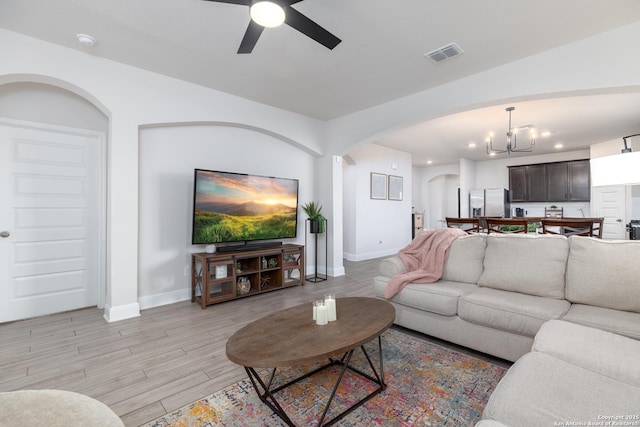 living room featuring ceiling fan with notable chandelier