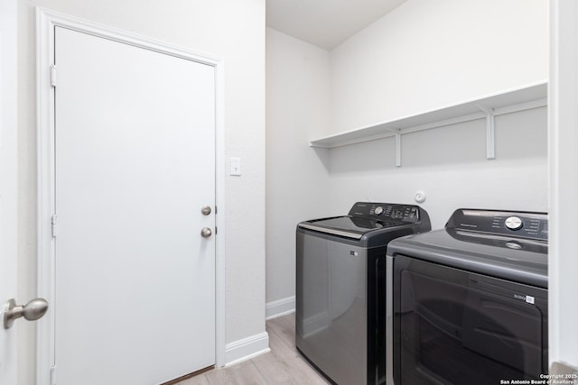 laundry room featuring washing machine and clothes dryer and light hardwood / wood-style flooring