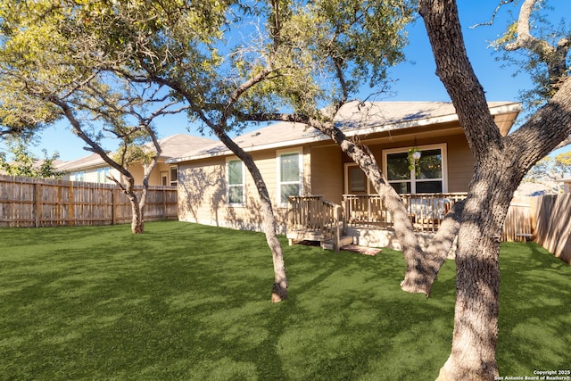 back of property featuring a wooden deck and a yard