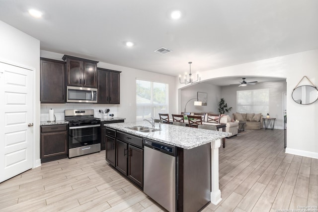 kitchen featuring a center island with sink, ceiling fan with notable chandelier, sink, appliances with stainless steel finishes, and decorative light fixtures