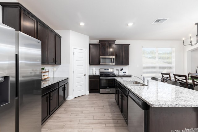 kitchen featuring pendant lighting, backsplash, sink, an island with sink, and stainless steel appliances