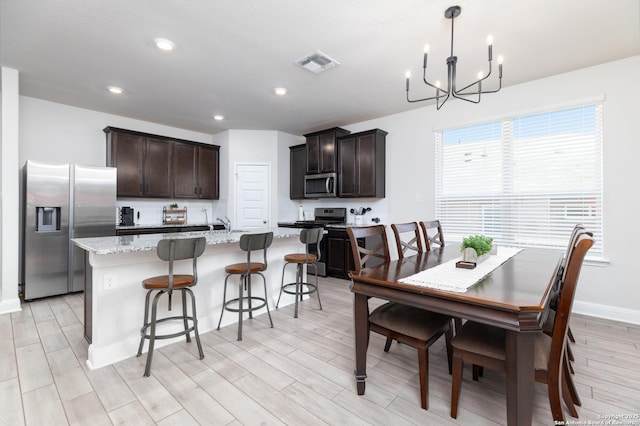 dining space with light hardwood / wood-style flooring and a chandelier