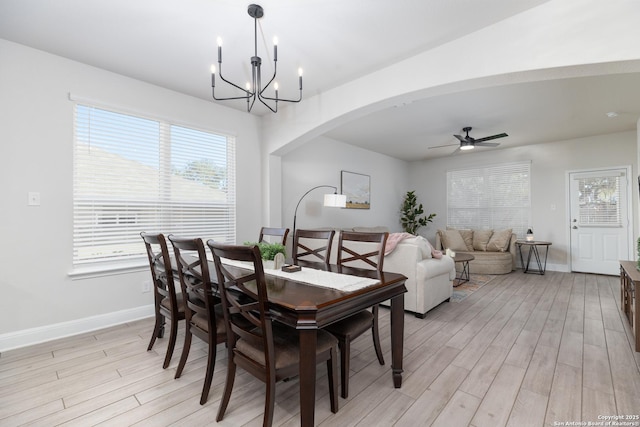 dining room with ceiling fan with notable chandelier and light wood-type flooring