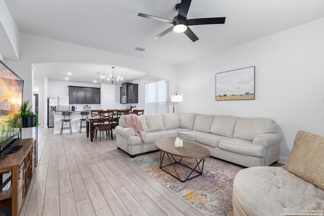 living room with ceiling fan with notable chandelier