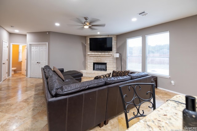 living room with ceiling fan and a fireplace