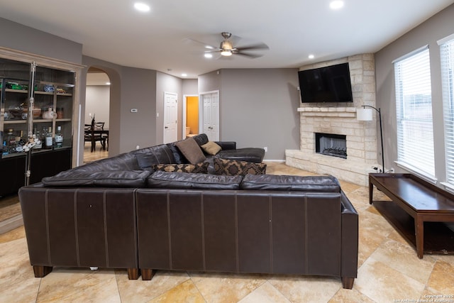 living room featuring a stone fireplace and ceiling fan