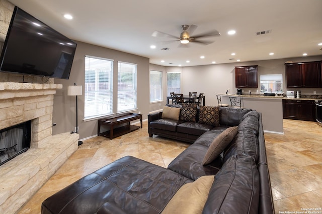 living room featuring a stone fireplace and ceiling fan