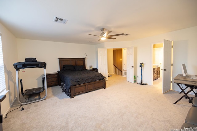 bedroom with ceiling fan, ensuite bathroom, and light carpet