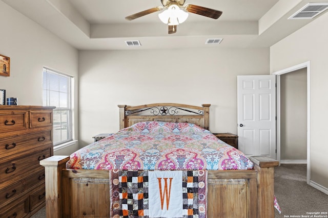 bedroom featuring carpet floors, a tray ceiling, and ceiling fan