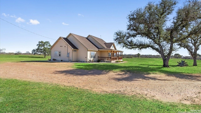 rear view of property featuring a porch and a yard