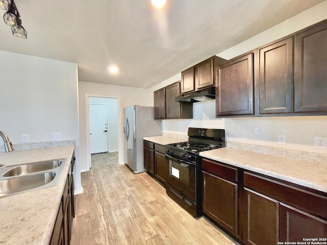 kitchen featuring sink, light hardwood / wood-style floors, dark brown cabinets, gas stove, and stainless steel refrigerator