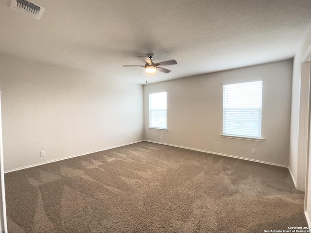 empty room featuring dark colored carpet, a textured ceiling, and ceiling fan