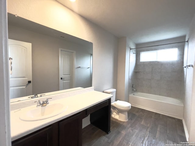 full bathroom with hardwood / wood-style floors, vanity, tiled shower / bath combo, and toilet