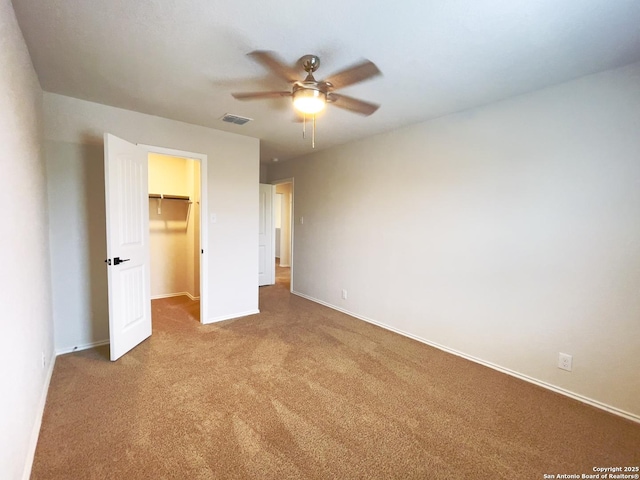 unfurnished bedroom featuring ceiling fan, a closet, carpet floors, and a spacious closet