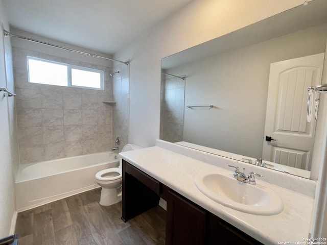 full bathroom featuring hardwood / wood-style floors, tiled shower / bath combo, toilet, and vanity