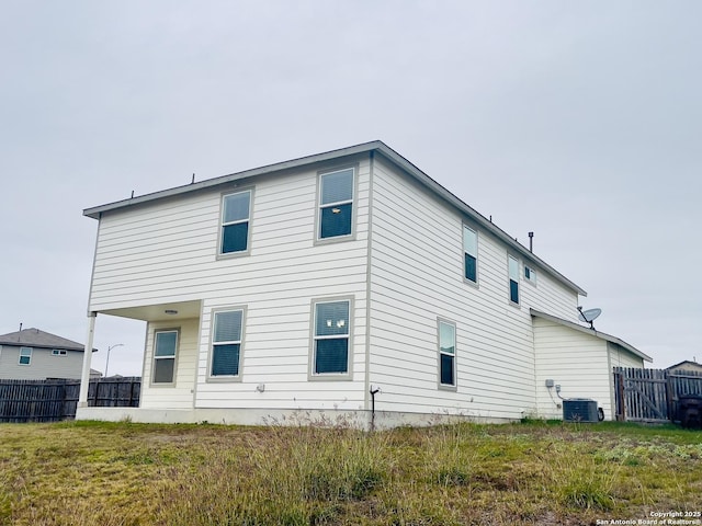 rear view of property featuring central air condition unit and a yard