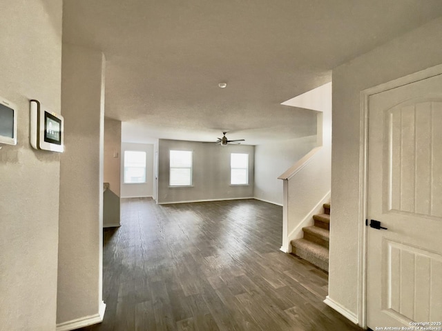 unfurnished living room with ceiling fan and dark wood-type flooring