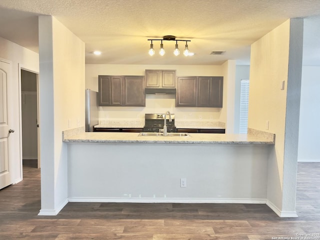 kitchen featuring stainless steel fridge, light stone counters, dark brown cabinetry, sink, and dark hardwood / wood-style floors