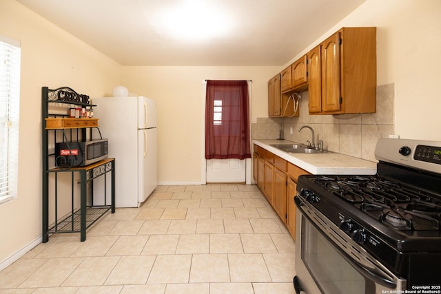 kitchen featuring tasteful backsplash, sink, light tile patterned flooring, and appliances with stainless steel finishes