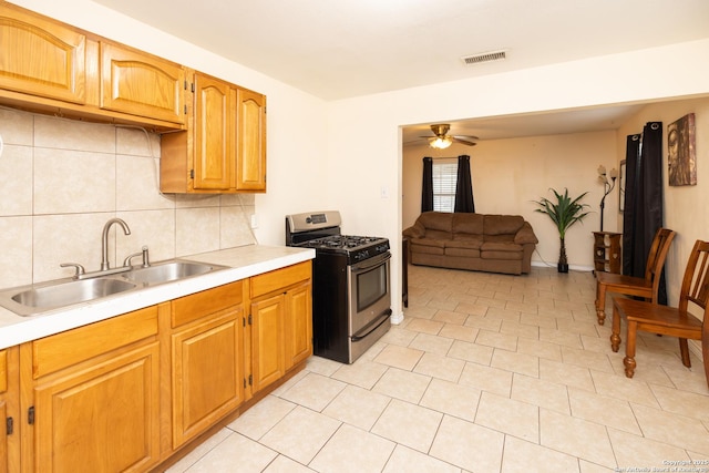 kitchen featuring decorative backsplash, ceiling fan, sink, light tile patterned floors, and stainless steel range with gas stovetop