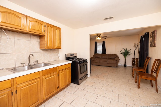 kitchen featuring decorative backsplash, ceiling fan, sink, light tile patterned floors, and black gas range