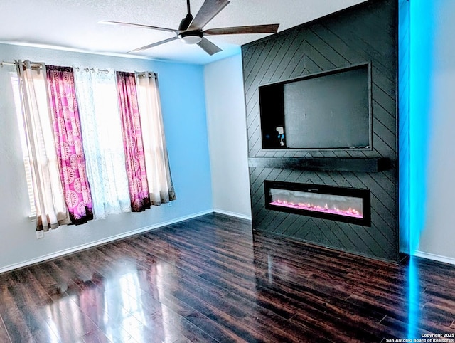 interior space featuring dark hardwood / wood-style flooring, ceiling fan, a large fireplace, and a textured ceiling