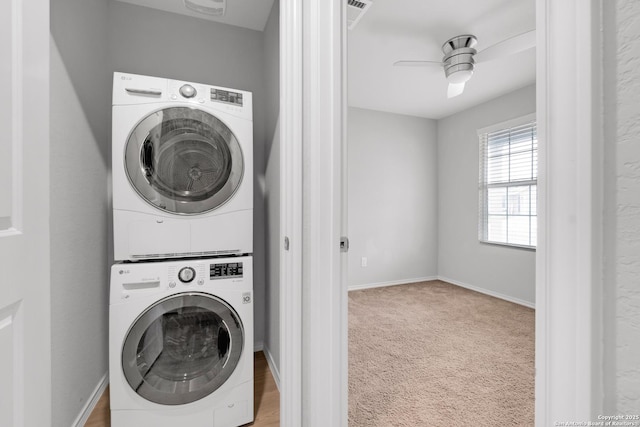 washroom featuring light carpet, stacked washing maching and dryer, and ceiling fan