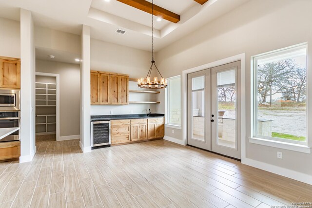 kitchen featuring stainless steel appliances, beverage cooler, a notable chandelier, decorative light fixtures, and light wood-type flooring