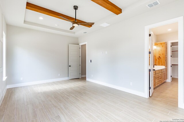 unfurnished room featuring a raised ceiling, ceiling fan, and beamed ceiling