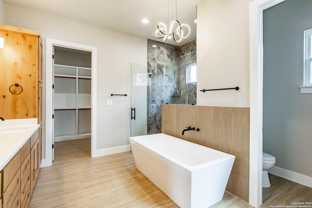 full bathroom with a chandelier, independent shower and bath, hardwood / wood-style flooring, and toilet