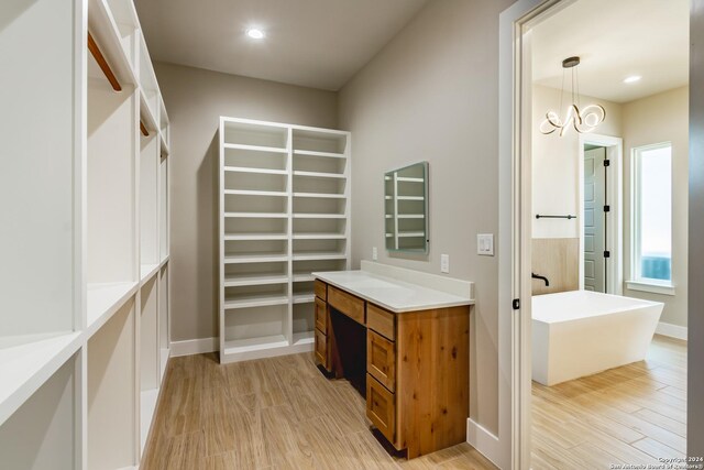 walk in closet featuring light hardwood / wood-style flooring and an inviting chandelier