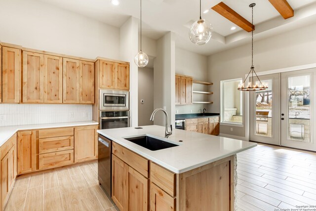 kitchen featuring light brown cabinets, sink, an island with sink, a notable chandelier, and stainless steel appliances