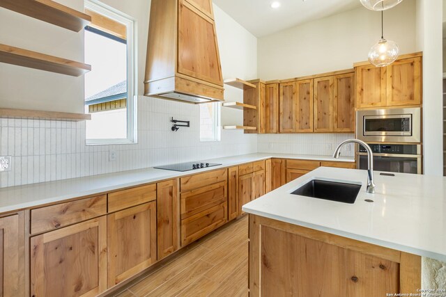 kitchen with sink, hanging light fixtures, tasteful backsplash, custom range hood, and appliances with stainless steel finishes