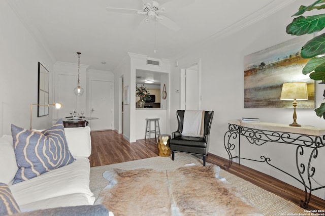 living area featuring visible vents, ornamental molding, wood finished floors, baseboards, and ceiling fan